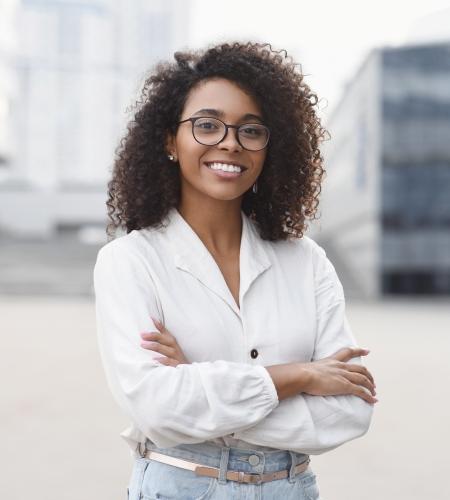 Smiling female business student standing in plaza with arms crossed